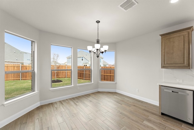 unfurnished dining area featuring a healthy amount of sunlight, baseboards, and a notable chandelier