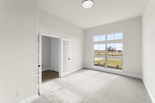carpeted spare room with french doors and baseboards