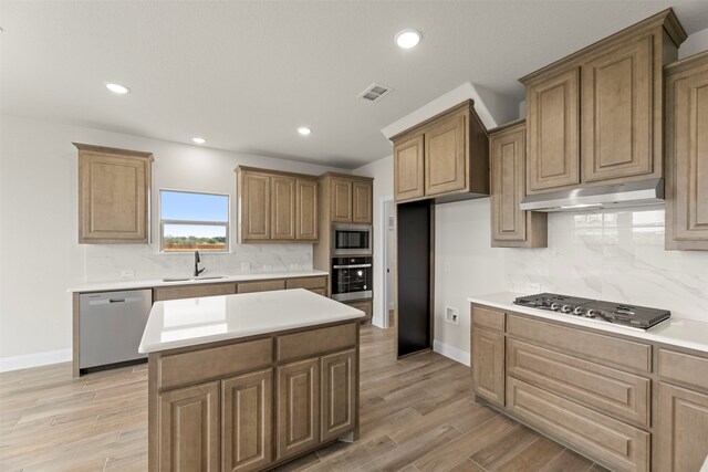 kitchen featuring tasteful backsplash, under cabinet range hood, visible vents, appliances with stainless steel finishes, and a sink