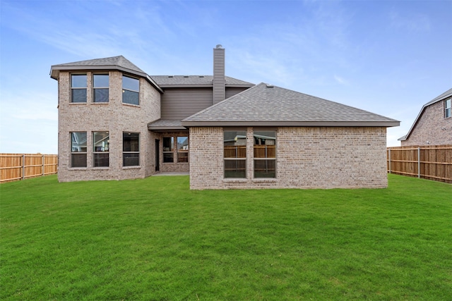 back of house with a yard, roof with shingles, and a fenced backyard