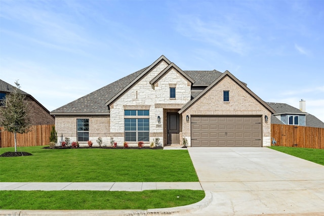 french country home featuring a front lawn, a shingled roof, stone siding, and fence