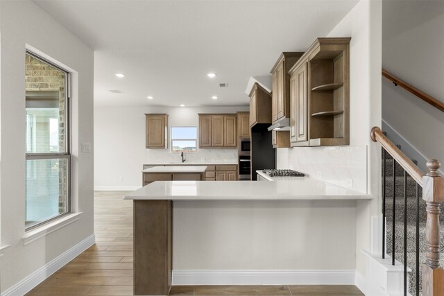 kitchen with a peninsula, decorative backsplash, light countertops, and open shelves