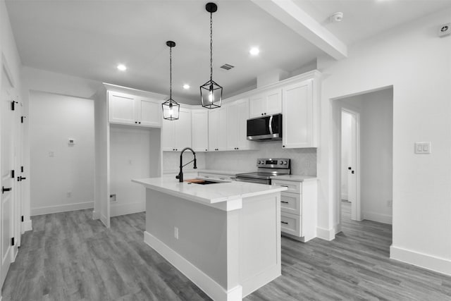 kitchen featuring appliances with stainless steel finishes, a sink, an island with sink, white cabinetry, and decorative backsplash