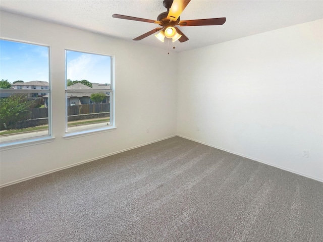 carpeted empty room featuring ceiling fan and baseboards