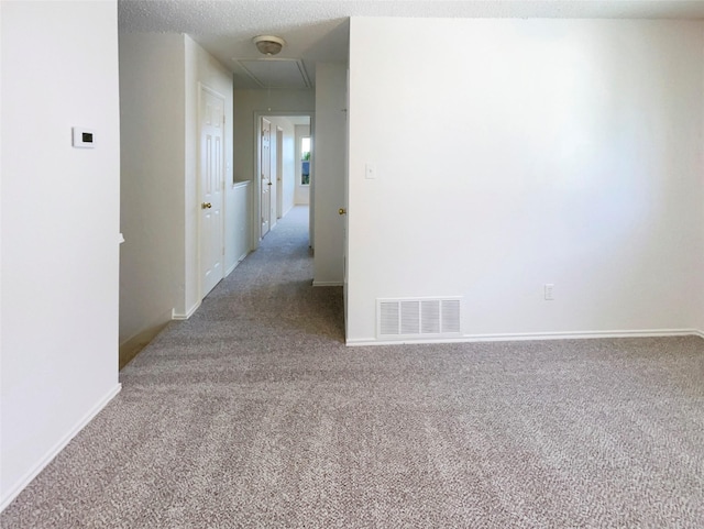 carpeted spare room featuring attic access, baseboards, and visible vents