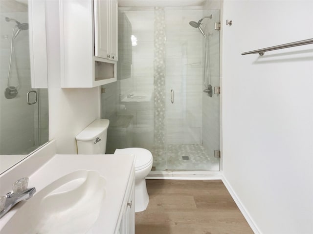 bathroom featuring toilet, a stall shower, wood finished floors, and vanity