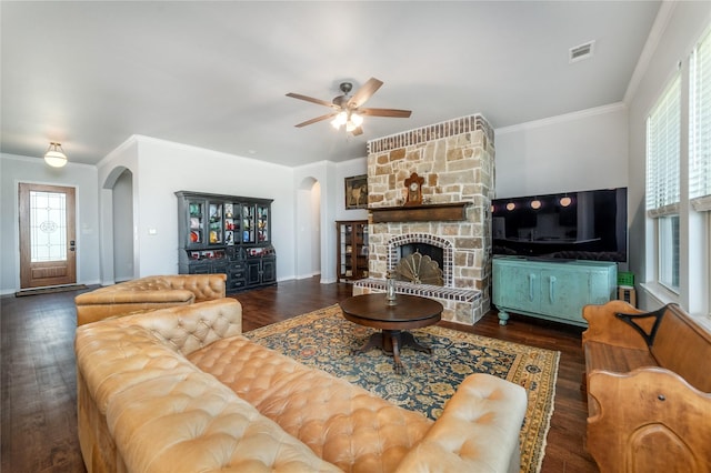 living room featuring arched walkways, ornamental molding, baseboards, visible vents, and a ceiling fan