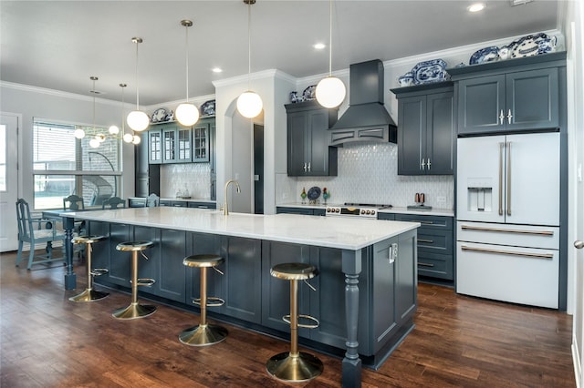 kitchen featuring decorative backsplash, stove, white refrigerator with ice dispenser, a spacious island, and custom exhaust hood