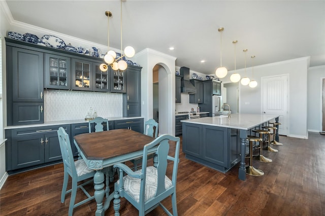 dining space featuring baseboards, recessed lighting, arched walkways, ornamental molding, and dark wood-style floors
