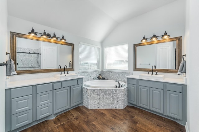 full bath featuring vaulted ceiling, wood finished floors, two vanities, and a sink