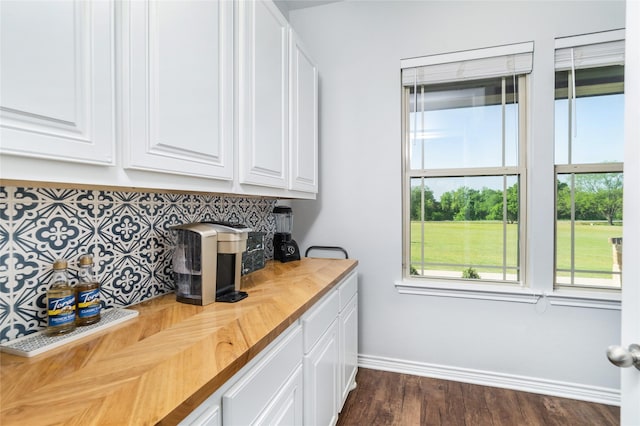bar featuring dark wood-type flooring, baseboards, and backsplash