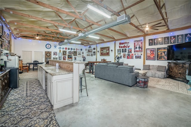 kitchen featuring a breakfast bar area, light stone countertops, concrete flooring, and open floor plan