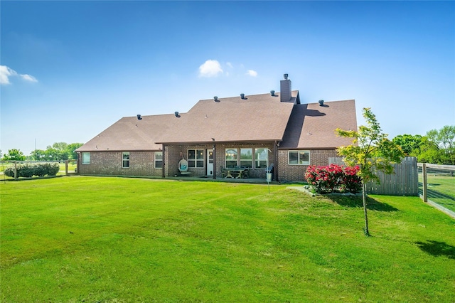 back of house with a chimney, brick siding, fence, and a lawn