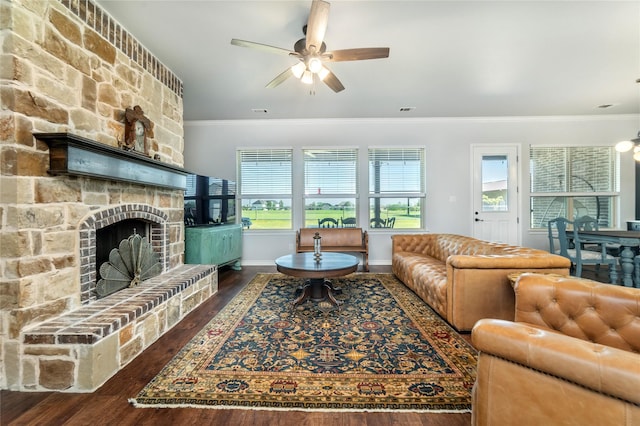 living area with a wealth of natural light, wood finished floors, crown molding, and a stone fireplace