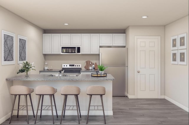 kitchen with a kitchen bar, light wood-style floors, white cabinetry, and stainless steel appliances
