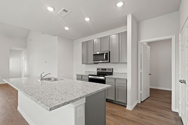 9952 Dynamics Dr, Fort Worth, TX 76131 - kitchen with appliances with stainless steel finishes, gray cabinets, a sink, dark wood finished floors, and light stone countertops