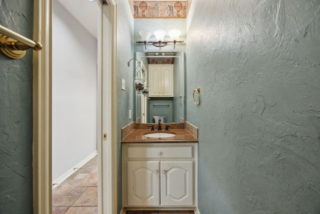 bathroom featuring baseboards, stone tile flooring, and vanity