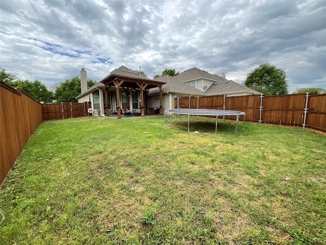 back of house with a fenced backyard, a chimney, a trampoline, a yard, and a patio