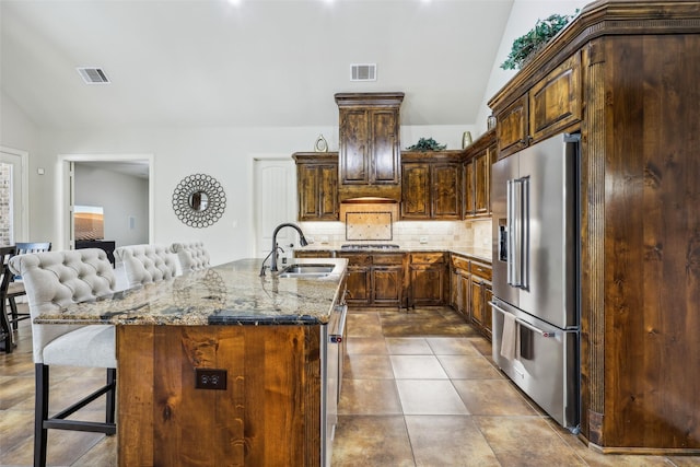 1011 Caribou Dr, Prosper, TX 75078 - kitchen with high end refrigerator, a sink, vaulted ceiling, backsplash, and light stone counters