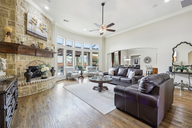 living area featuring arched walkways, a ceiling fan, visible vents, and ornamental molding