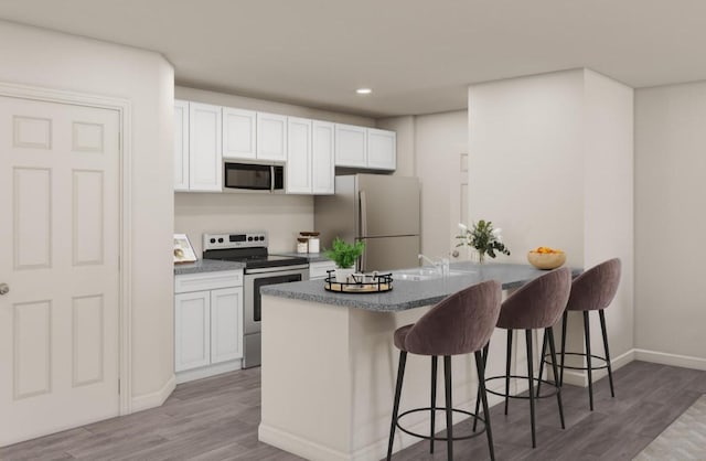 kitchen featuring light wood finished floors, a kitchen breakfast bar, white cabinets, and stainless steel appliances