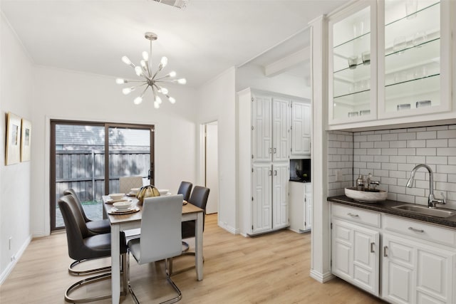 dining space with light wood-type flooring, an inviting chandelier, and baseboards