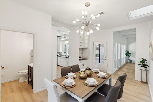 dining space featuring light wood-style flooring, a notable chandelier, and baseboards