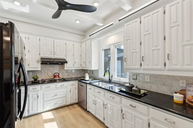 kitchen with dark countertops, appliances with stainless steel finishes, a sink, and under cabinet range hood