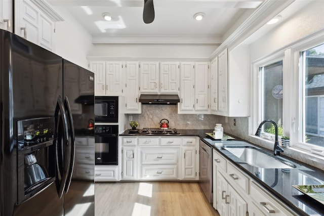kitchen featuring under cabinet range hood, a sink, black appliances, and a healthy amount of sunlight