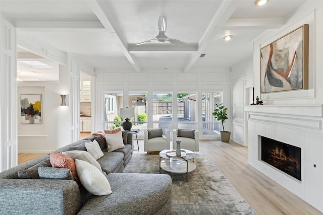 living area featuring a wealth of natural light, a decorative wall, light wood-style flooring, and coffered ceiling
