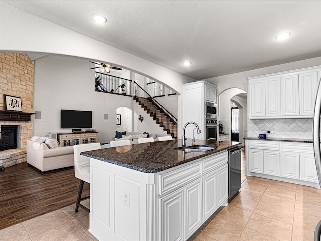 kitchen featuring open floor plan, ceiling fan, stainless steel appliances, arched walkways, and a sink