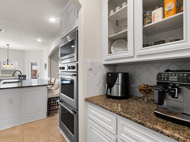 kitchen featuring decorative backsplash, a sink, dark stone counters, and appliances with stainless steel finishes