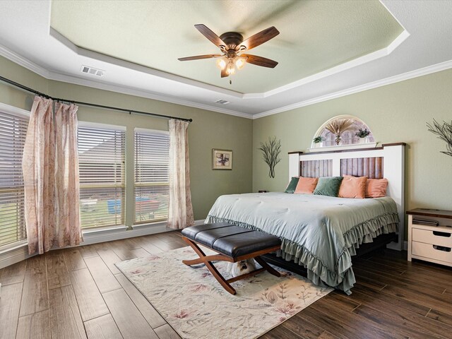 bedroom featuring multiple windows, a raised ceiling, and hardwood / wood-style floors