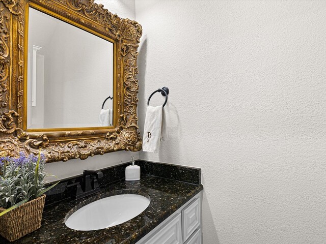 bathroom with a textured wall and vanity
