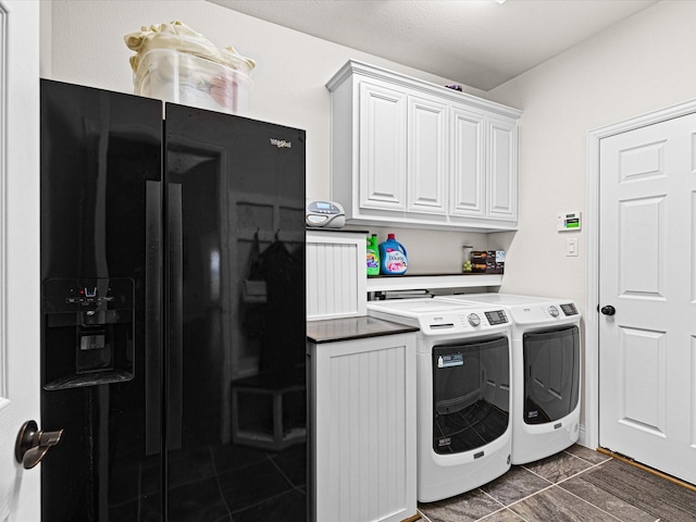 washroom featuring dark tile patterned floors, washer and clothes dryer, and cabinet space