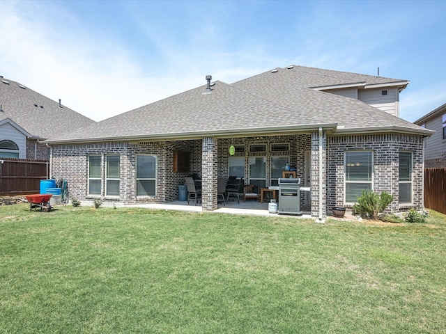 back of house featuring fence, a patio, a shingled roof, and a lawn