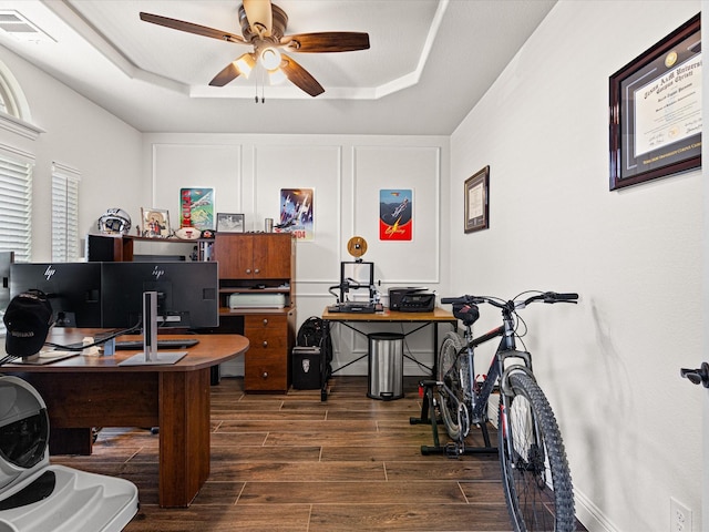 office space with dark wood-type flooring, visible vents, a ceiling fan, and a raised ceiling
