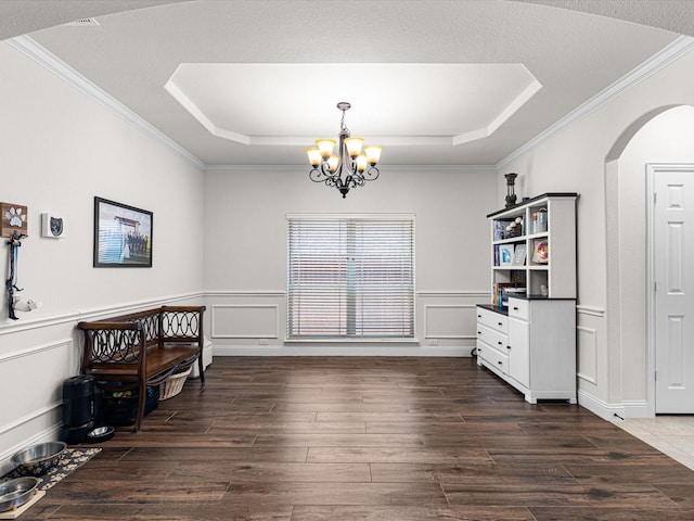 dining area featuring ornamental molding, a raised ceiling, arched walkways, and dark wood finished floors