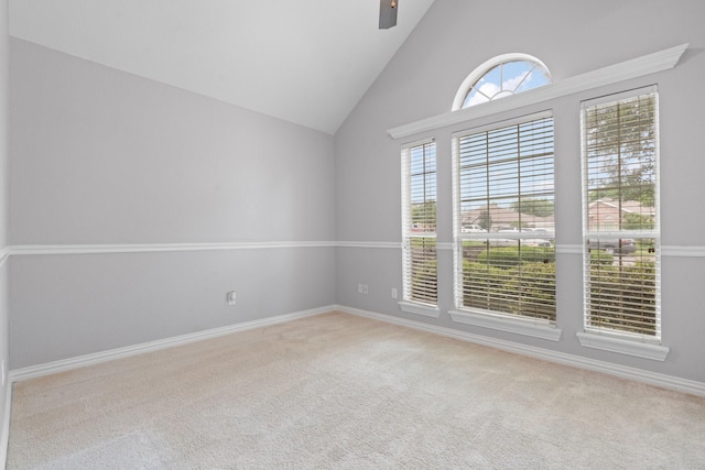 carpeted spare room featuring a ceiling fan, high vaulted ceiling, and baseboards