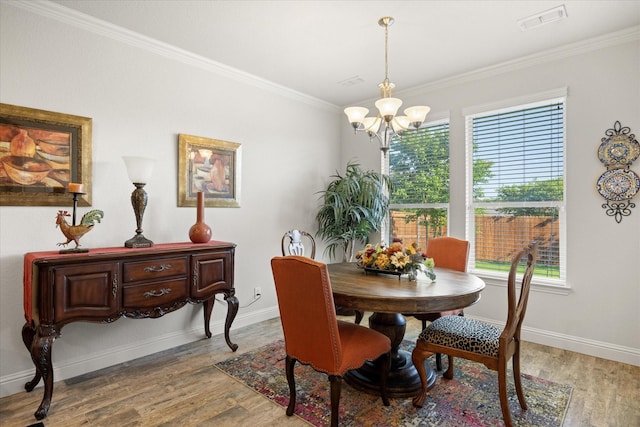 dining area featuring visible vents, light wood-type flooring, an inviting chandelier, and crown molding