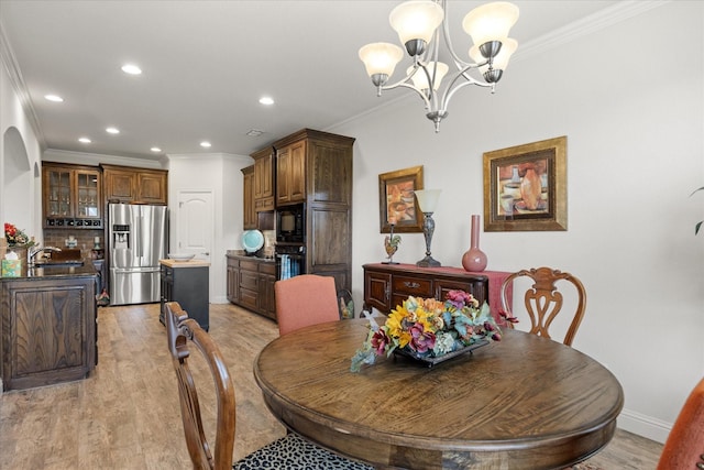 dining area with an inviting chandelier, recessed lighting, light wood finished floors, and crown molding