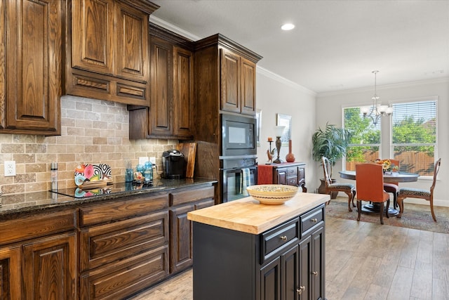 kitchen featuring crown molding, an inviting chandelier, black appliances, butcher block countertops, and decorative backsplash