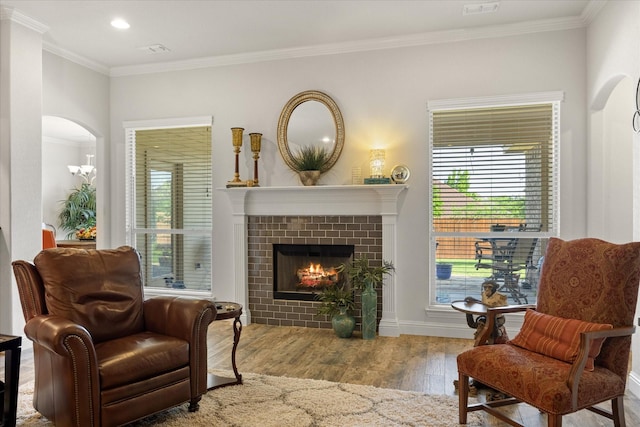sitting room featuring arched walkways, ornamental molding, a fireplace, recessed lighting, and wood finished floors