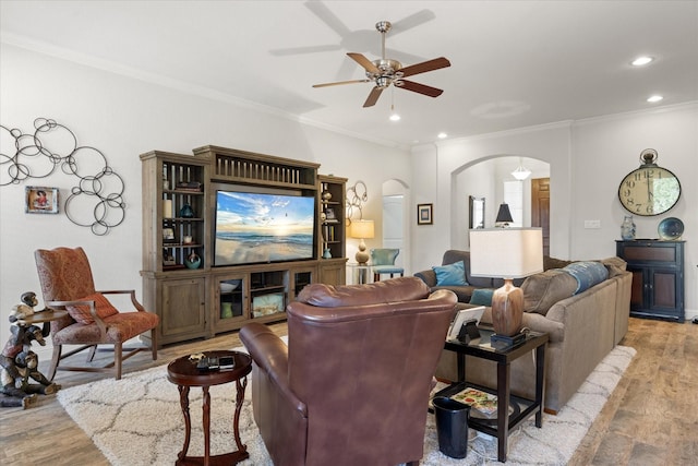 living area with arched walkways, ornamental molding, a ceiling fan, recessed lighting, and wood finished floors