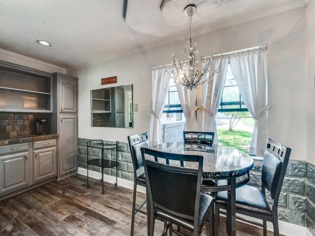 dining space with dark wood-style flooring, baseboards, ornamental molding, a chandelier, and a textured ceiling