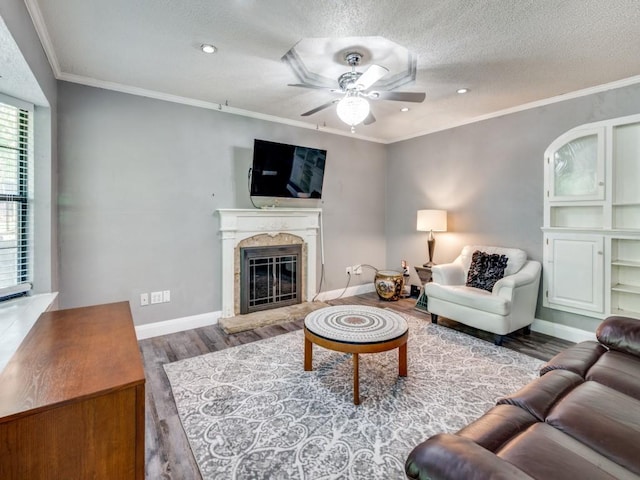 living area with baseboards, a textured ceiling, wood finished floors, ceiling fan, and a premium fireplace