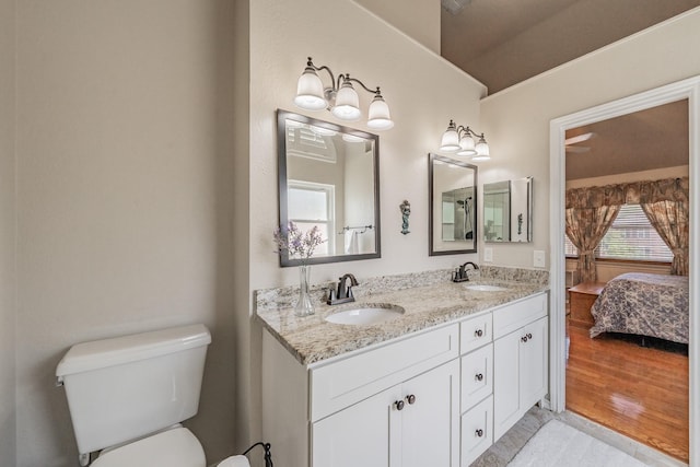 ensuite bathroom featuring connected bathroom, double vanity, a sink, and toilet