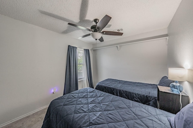 carpeted bedroom with a textured ceiling, ceiling fan, baseboards, and visible vents
