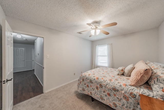 carpeted bedroom featuring a textured ceiling, baseboards, a ceiling fan, and visible vents
