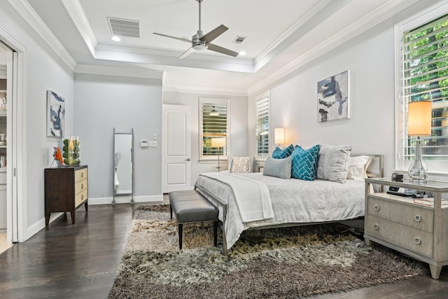 bedroom with arched walkways, wood finished floors, visible vents, and a tray ceiling
